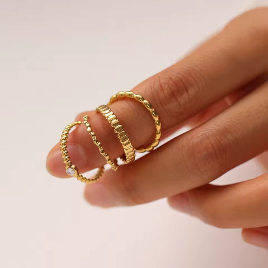 Gold rings on a finger against a plain background