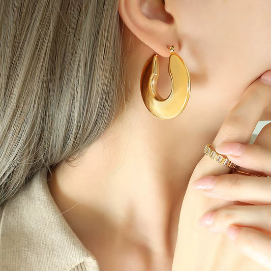Gold hoop earrings worn by a person with a neutral background