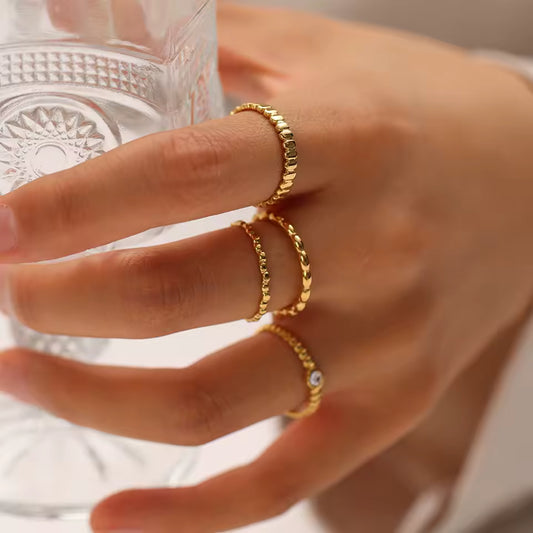 Hand wearing two gold rings with a blurred background