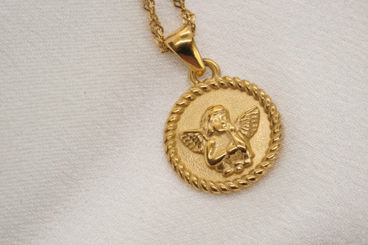 Gold pendant with an angel design on a light gray background