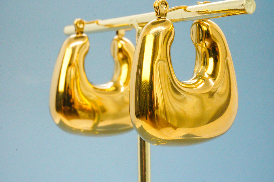 Lunara Earrings – Gold chunky hoop earrings on blue backdrop, minimal product shot by Luzza Studio