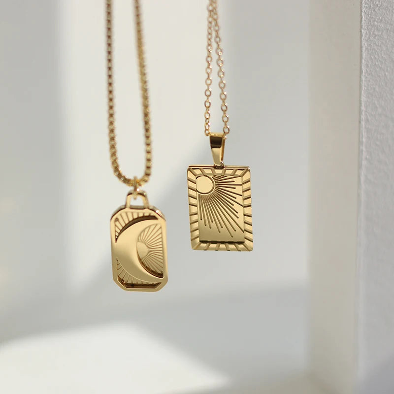 Two gold necklaces with geometric pendants on a light background