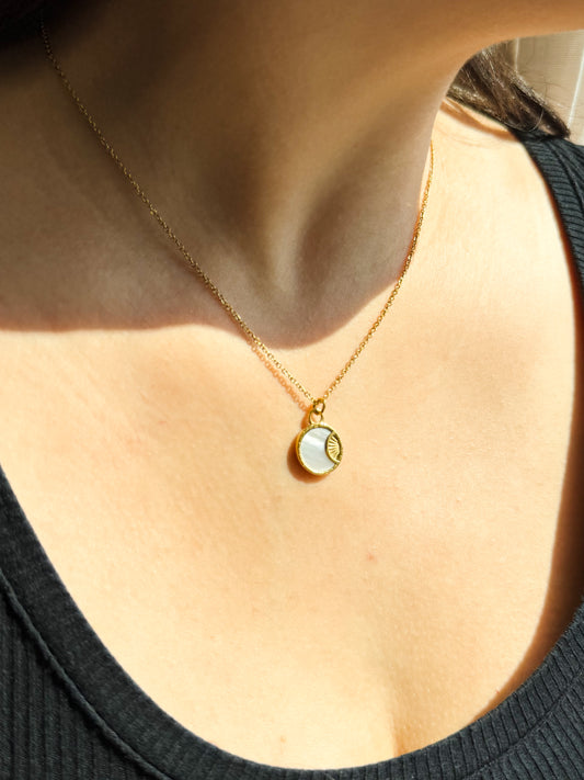 Gold necklace with a pendant worn by a person