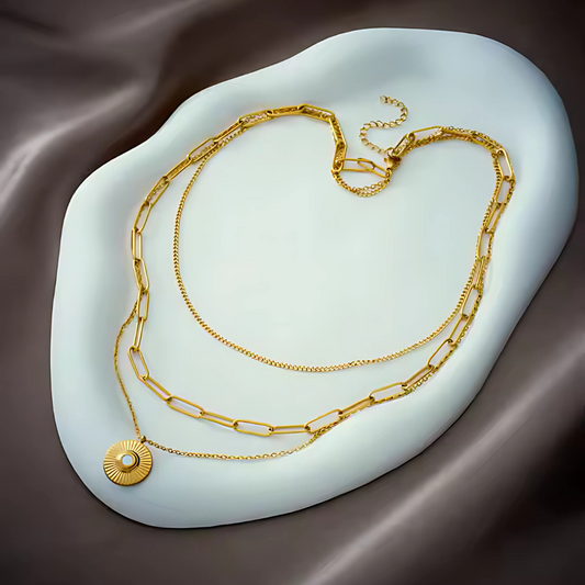 Gold chain necklace on a white stone surface