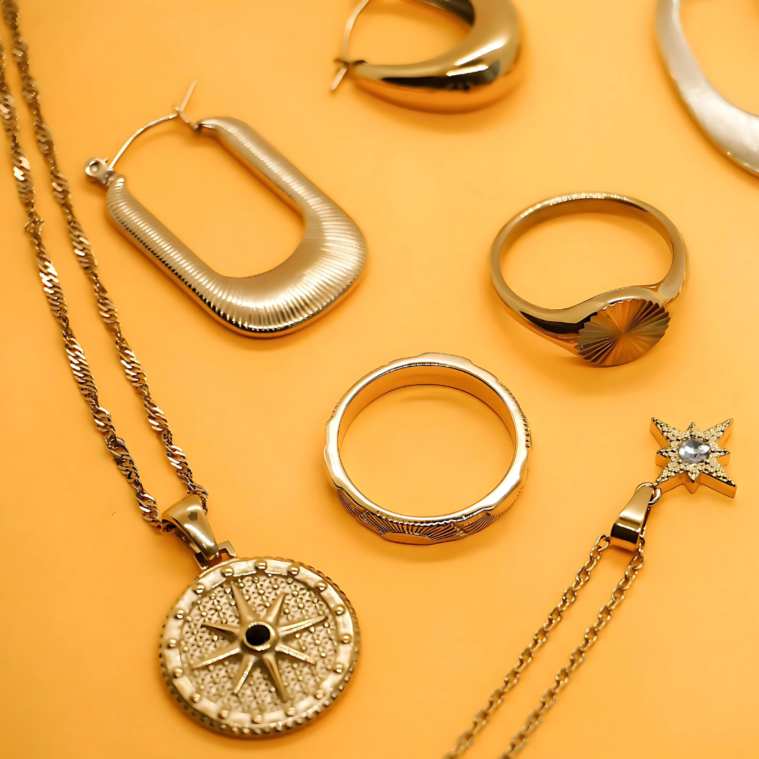 Gold jewelry including earrings, rings, and a necklace on an orange background