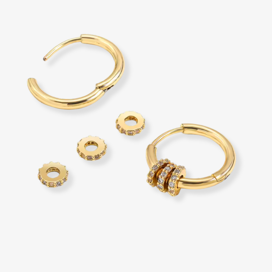 Set of gold hoop earrings with additional components on a white background