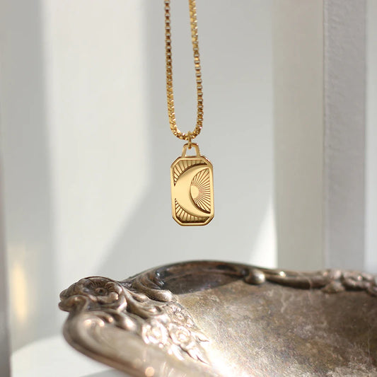 Gold necklace with a pendant on a decorative object against a neutral background