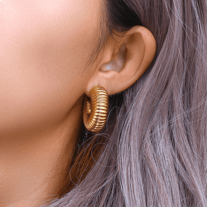 Gold hoop earring worn by a person with gray hair