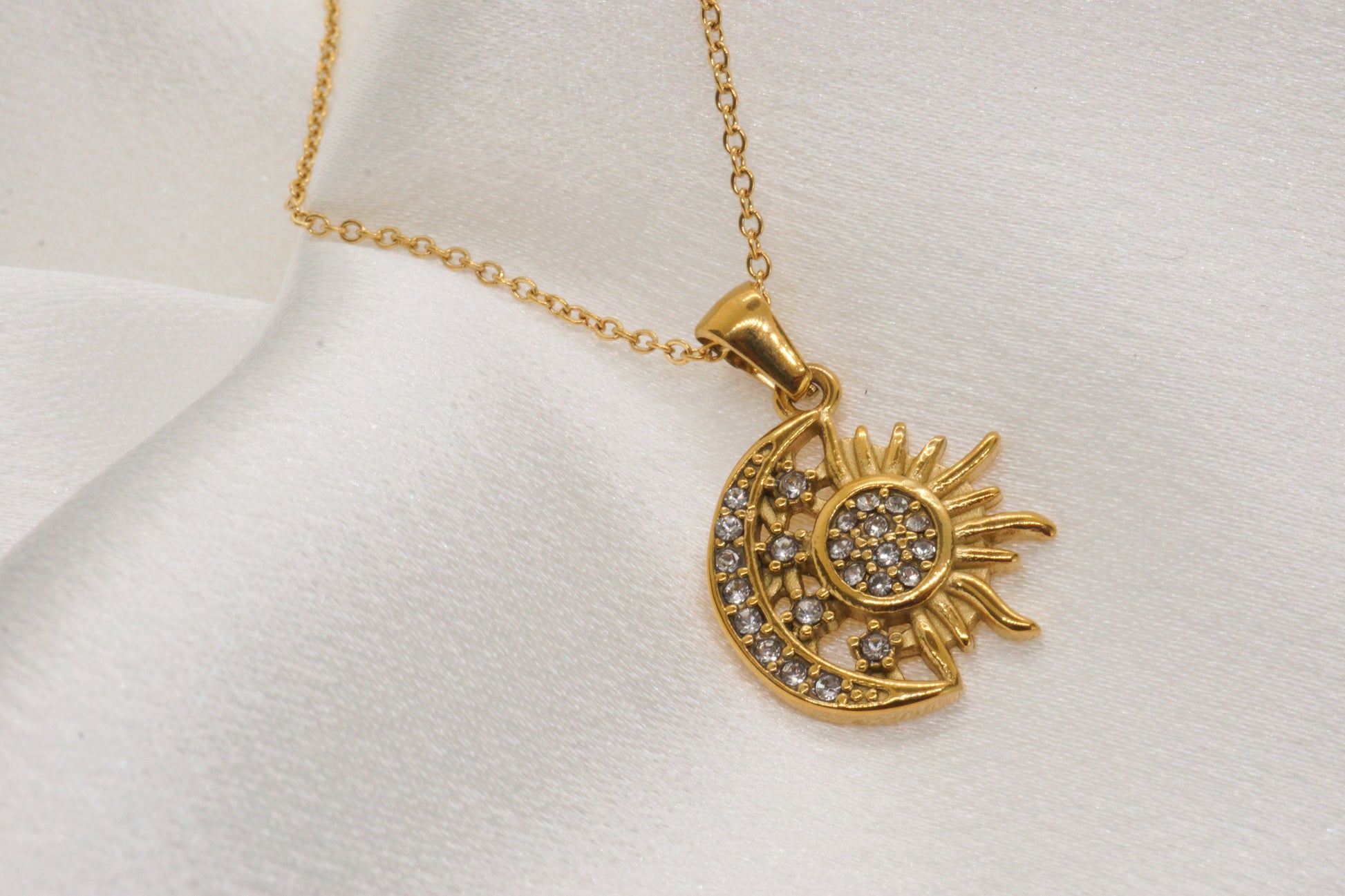 Gold necklace with sun and moon pendant on a white background